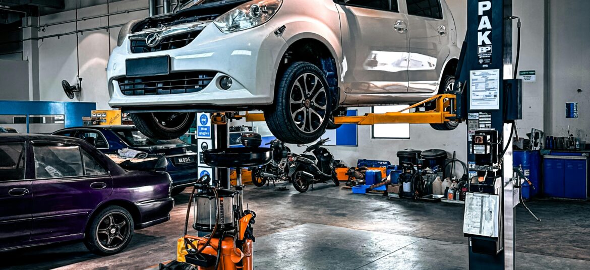 A car is lifted on a hydraulic lift in a well-equipped auto repair shop.