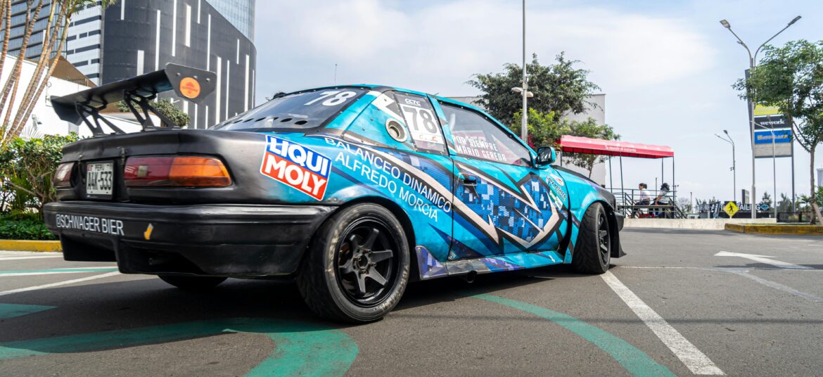 A colorful racing car with decals parked on a city street under a clear sky.